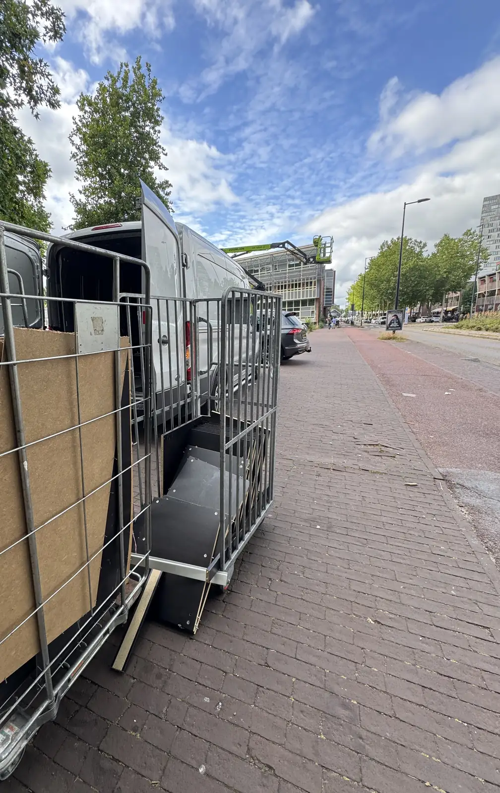 Rolcontainer met gedemonteerde kastpanelen naast de bus in Amsterdam